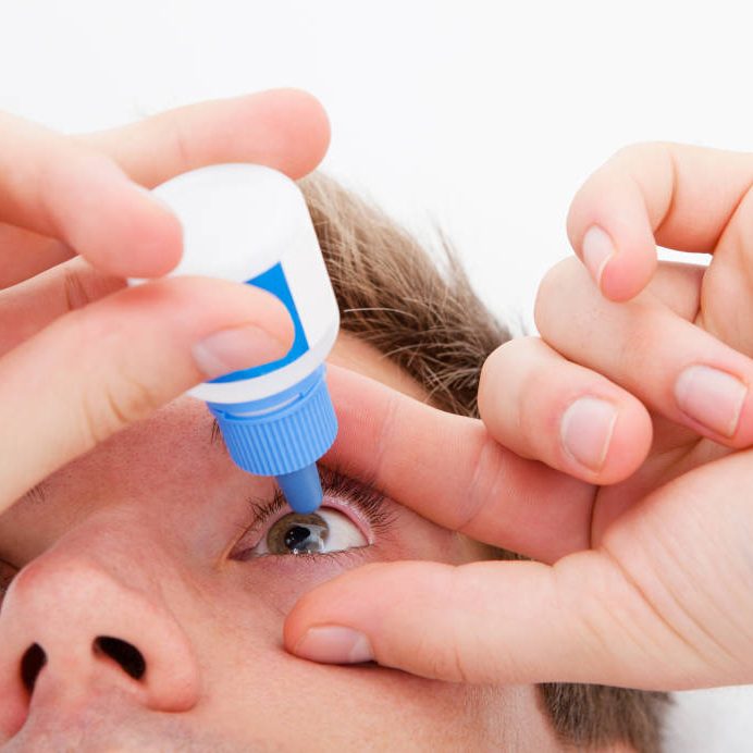 Closeup of man pouring drops in her eyes