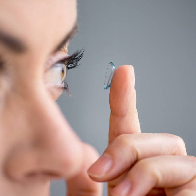 Attractive mature lady putting on contact lenses in her eyes